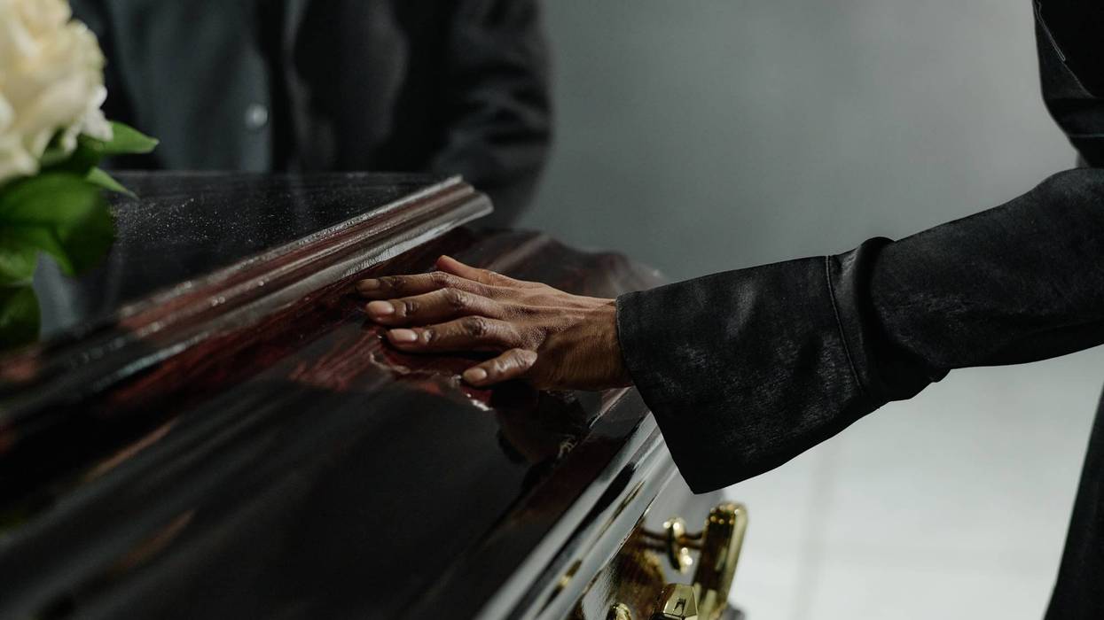 Middle Aged Black Woman Touching Coffin during Funeral Ceremony Indoors