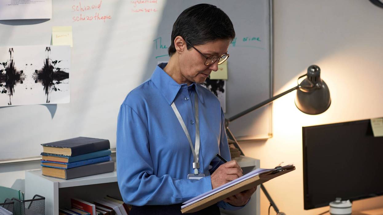 Middle Aged Caucasian Woman Writing Notes during Prison Psychological Evaluation