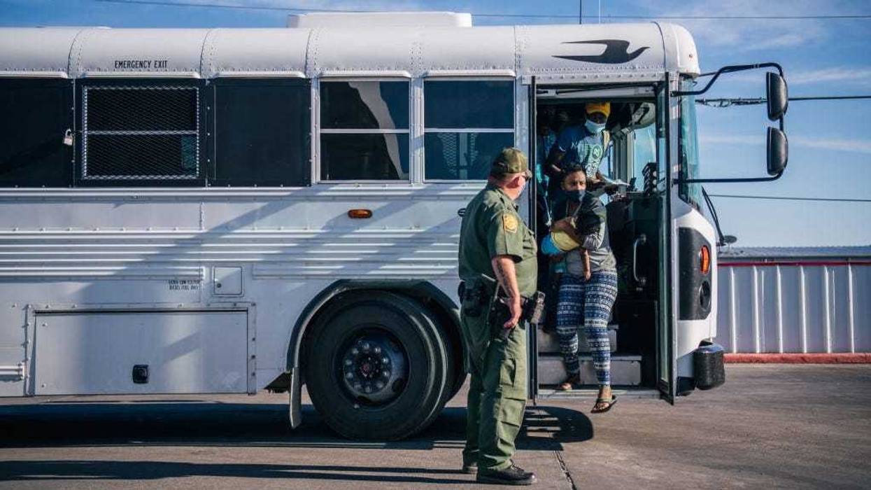 Migrants exit a Border Patrol bus and prepare to be received by the Val Verde Humanitarian Coalition after crossing the Rio Grande on September 22, 2021 in Del Rio, Texas.