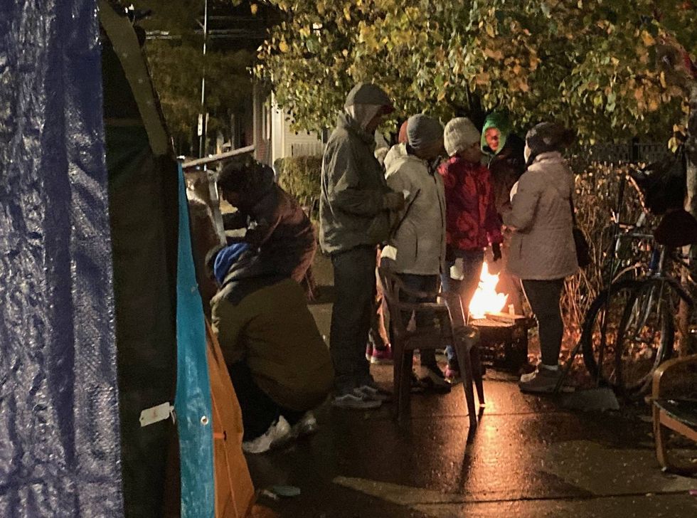 migrants huddled around grill