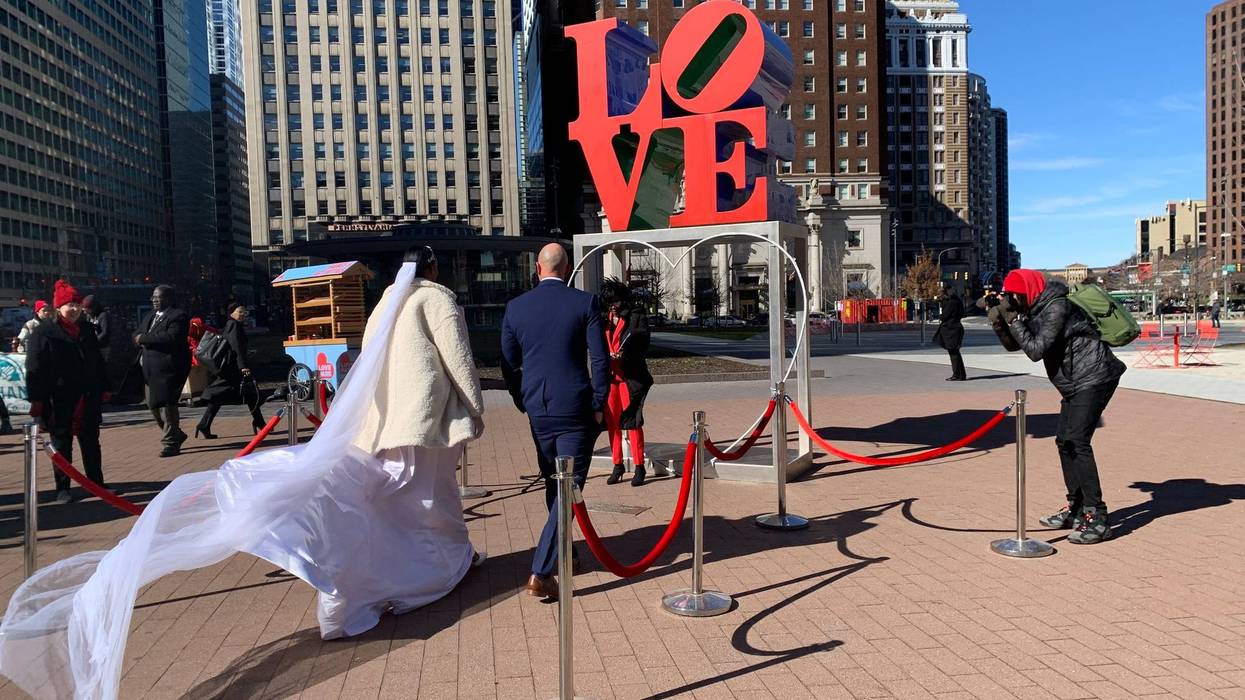 Mike Snader and Amy Brown walk towards Philadelphia Mayor Cherelle Parker, who officiated their wedding in LOVE Park.