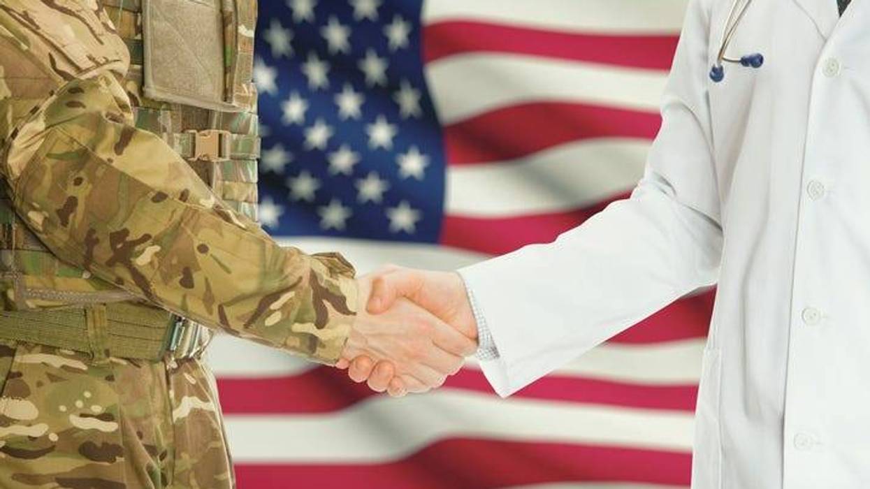 Military man in uniform and doctor shaking hands with U.S. flag in background