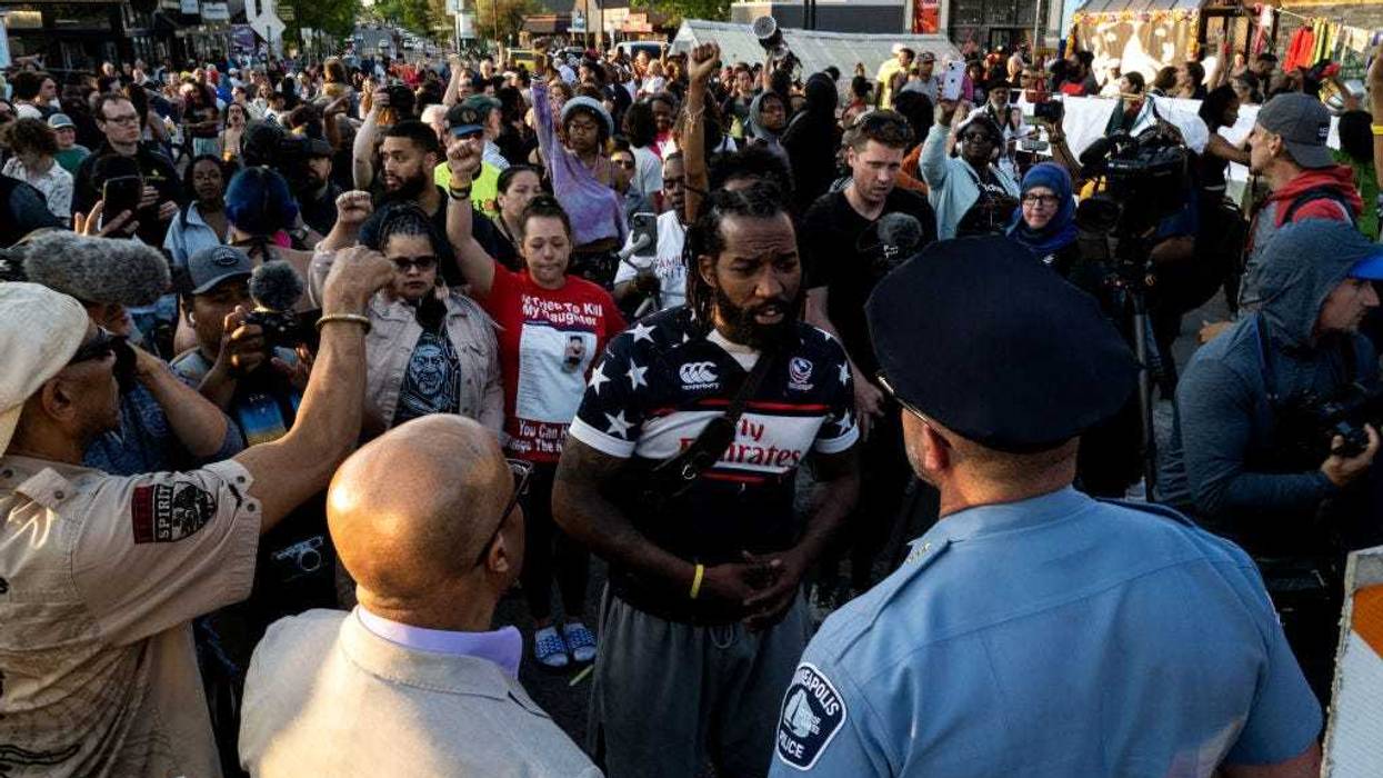 Minneapolis Police Chief Brian O'Hara (L) and former Chief Medaria Arradondo (R) are confronted as they arrive for a vigil at George Floyd Square on May 25, 2023 in Minneapolis, Minnesota.