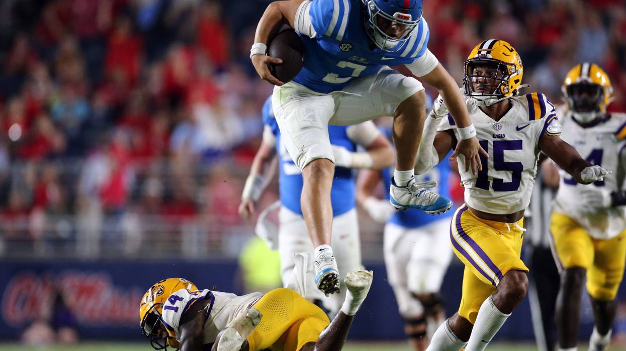 Mississippi Rebels quaterback Jaxson Dart leaps over LSU Tigers defensive back Andre' Sam
