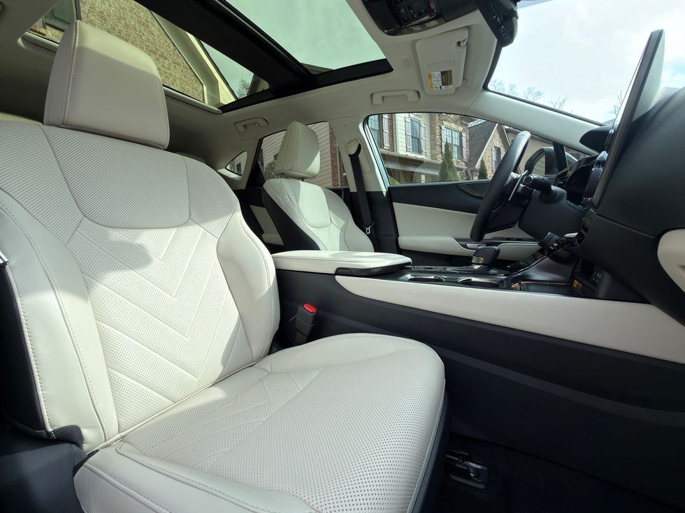 Modern car interior with light cream perforated leather seats, a large infotainment screen, and sunroof.