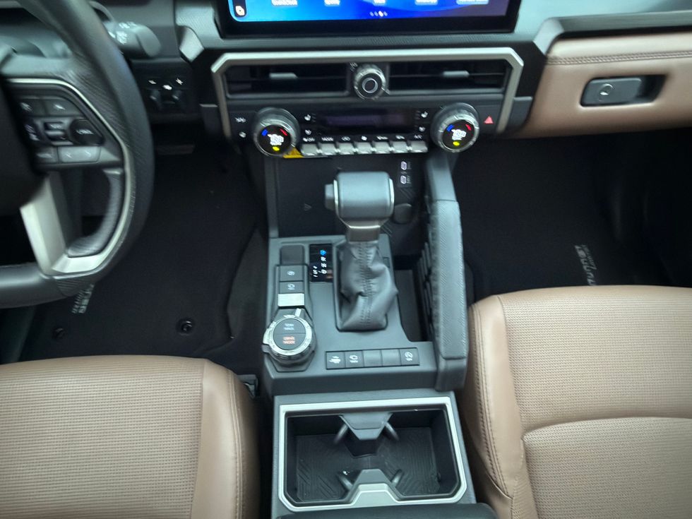 Modern car interior with steering wheel, digital display, automatic shifter, and brown leather seats.