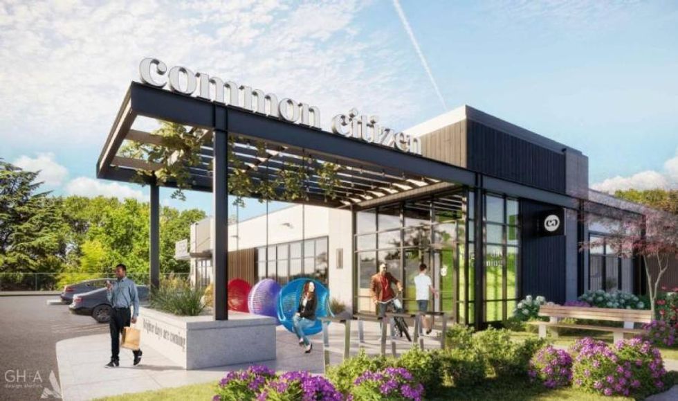 Modern geometric building with large windows along the front and side. An awning made of wooden slats features hanging plants. Vivid flowers and trees make up the landscaping.