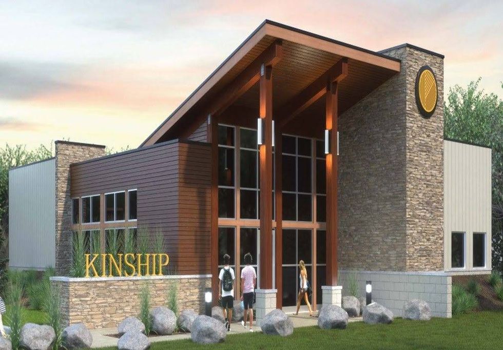 Modern warehouse-style building with a brick and mahogany storefront. Tall wooden pillars hold up an angled roof.