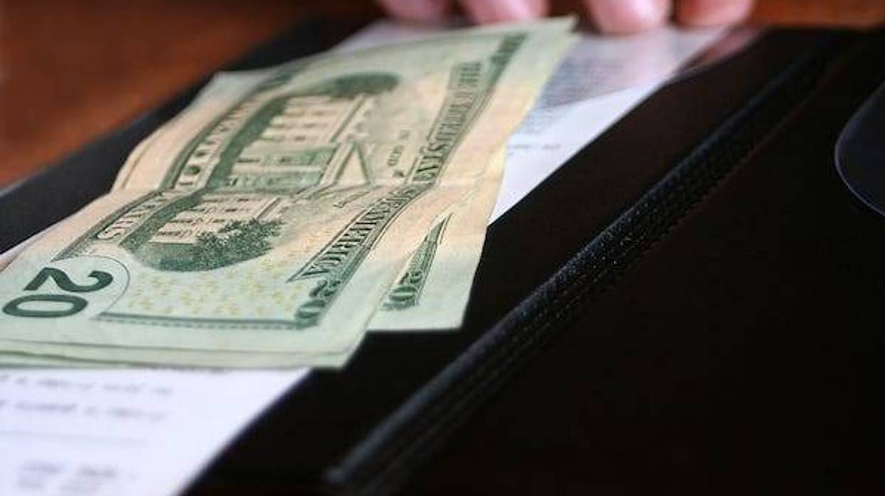 Money and receipt being placed on the payment binder for payment of a meal