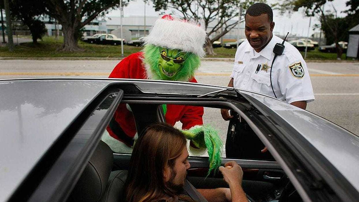 Monroe County Sheriff's Colonel Lou Caputo, dressed as the Grinch, and Monroe County Sheriff deputy James Jenkins warn a driver that he was driving too fast through a school zone December 19, 2008, in Marathon, Florida. Lieutenant Caputo wears the Grinch custom as part of a campaign to bring attention to the fact that people need to drive carefully, follow the posted speed limit and wear their seatbelts. (Photo by Joe Raedle/Getty Images)