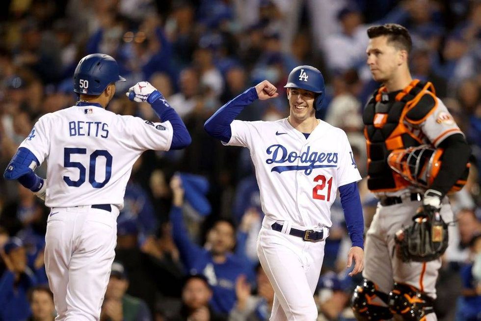 Mookie Betts #50 celebrates his two-run home run with Walker Buehler #21 of the Los Angeles Dodgers in front of Buster Posey #28 of the San Francisco Giants during the fourth inning in game 4.