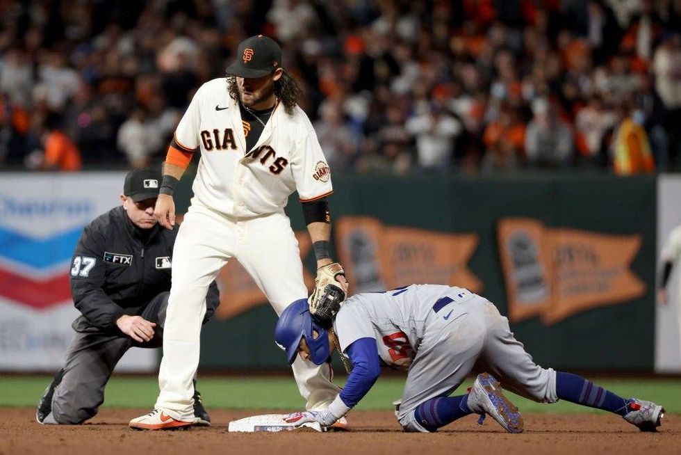Mookie Betts #50 of the Los Angeles Dodgers reacts in front of Brandon Crawford #35 of the San Francisco Giants after stealing second base during the sixth inning.