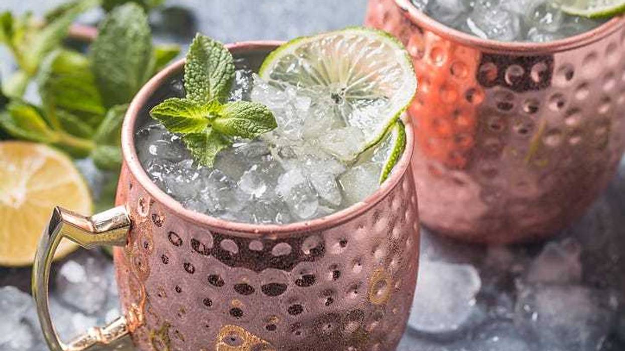 Moscow mule cocktail in copper cup with lime, ginger beer, vodka and mint garnish