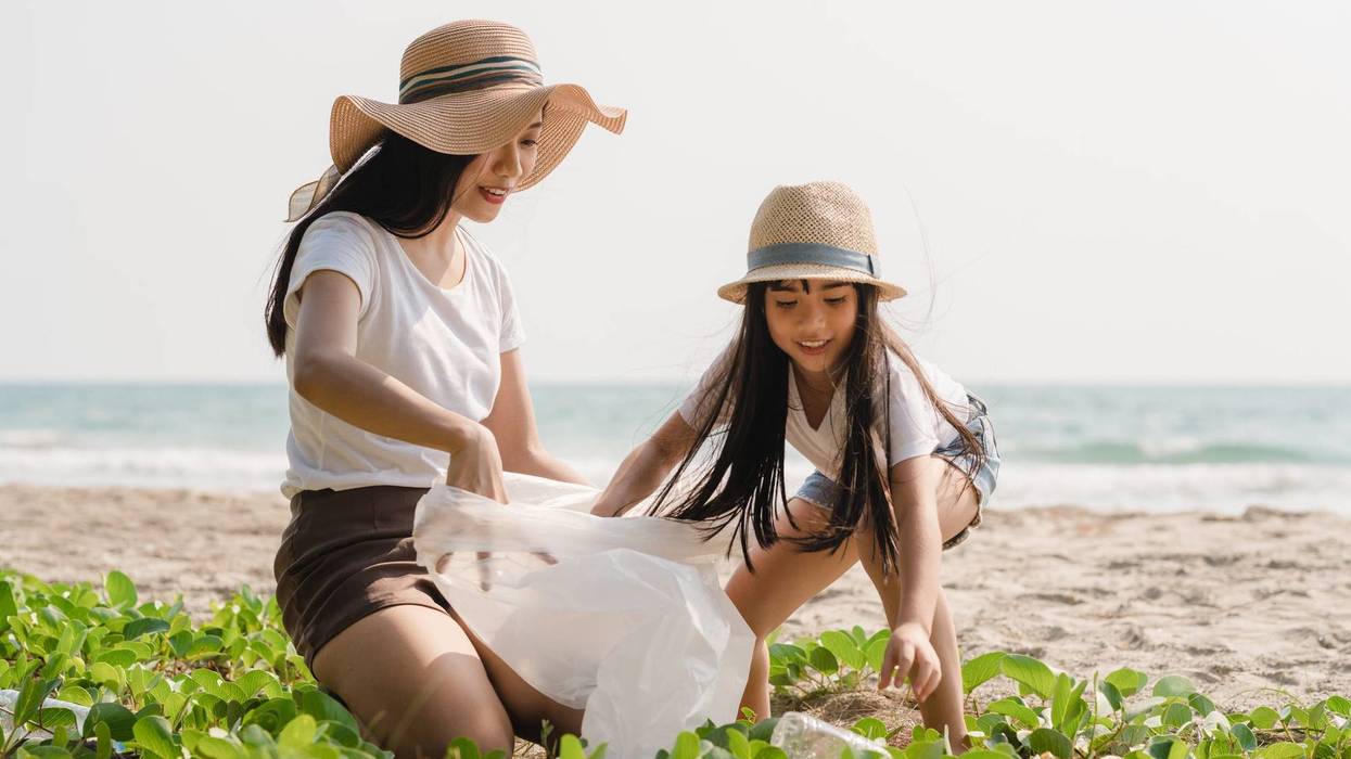 Mother and daughter picking up trash by beach