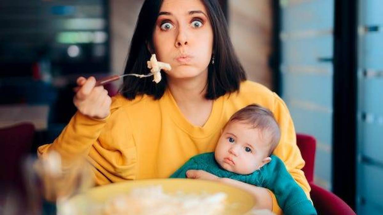 Mother eating while holding her baby at a restaurant