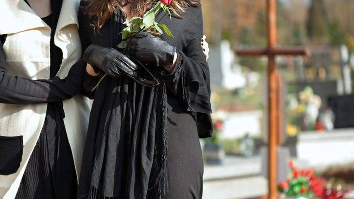 Mother holding her daughter standing above grave of family member