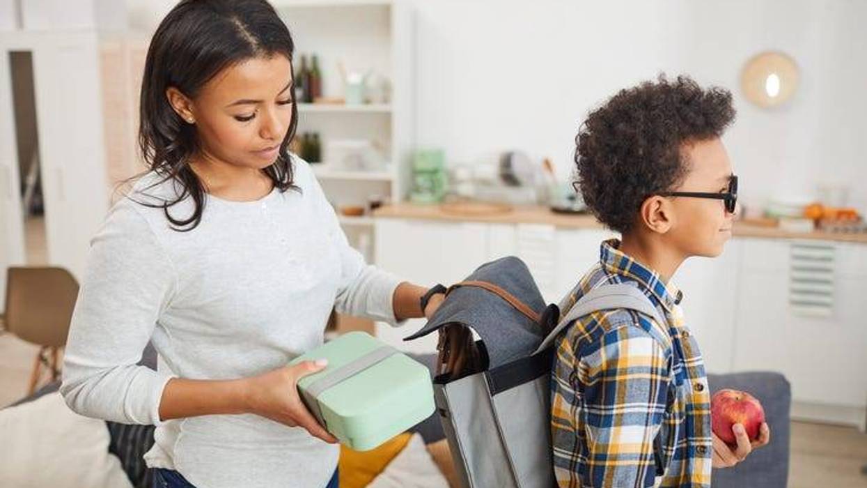mother packs son's backpack for school