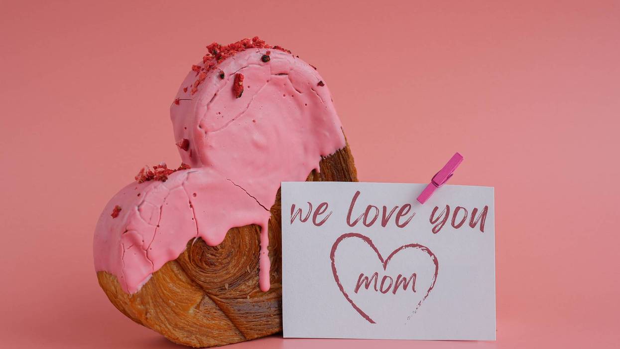 Mother's Day WE LOVE YOU MOM wishes saying caption on greeting card Delightful heartshaped pastry croissant treat, beautifully topped with colorful frosting galore. Copy space. Food experimentation viral dessert creative baking trend
