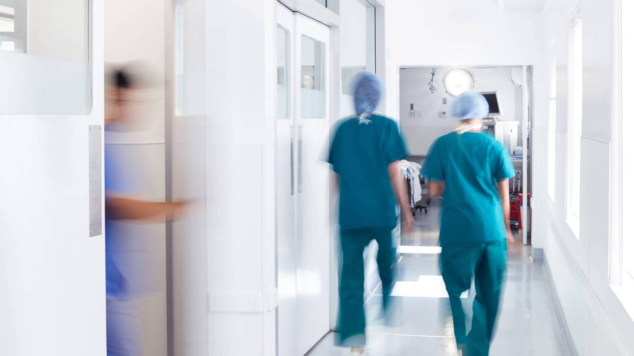 Motion Blur Shot Of Medical Staff Wearing Scrubs In Busy Hospital Corridor