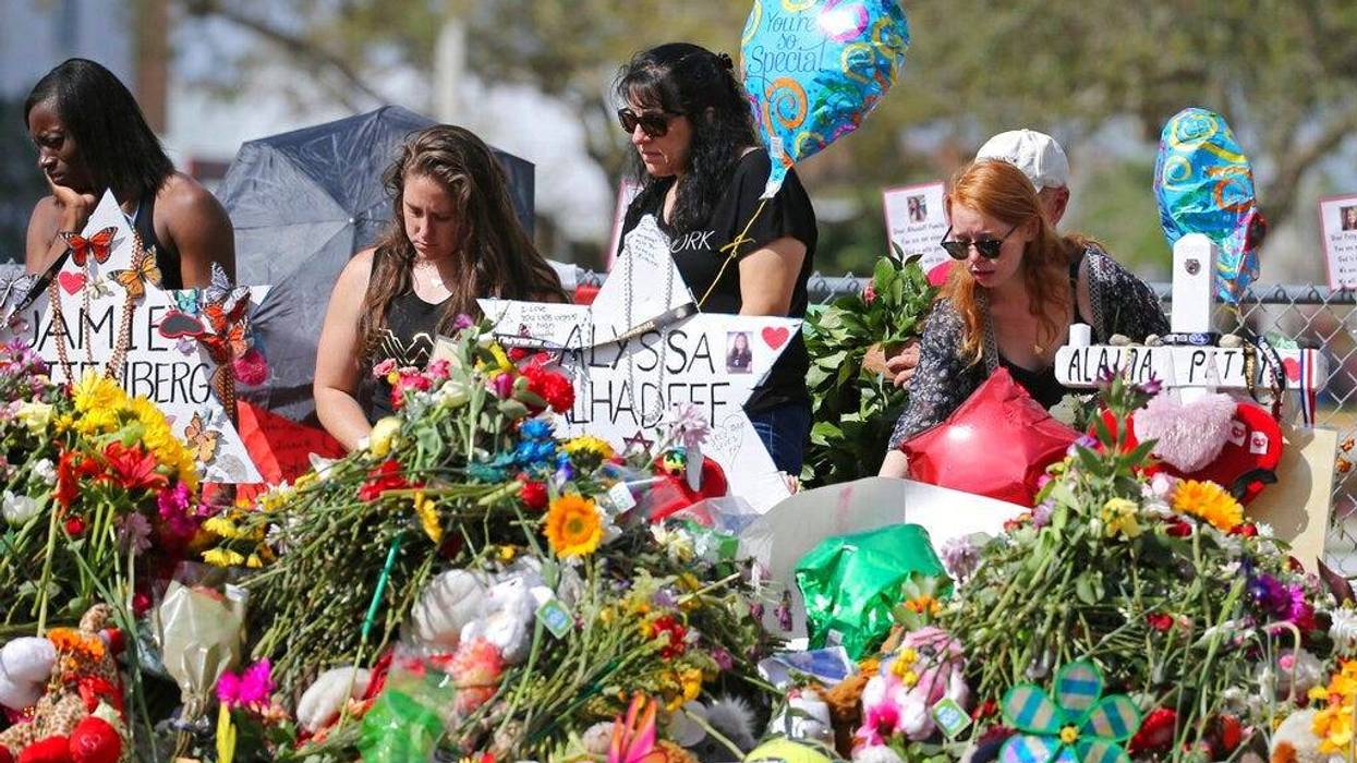 mourners bring flowers as they pay tribute at a memorial for the victims of the shooting at Marjory Stoneman Douglas High School, in Parkland, Fla.