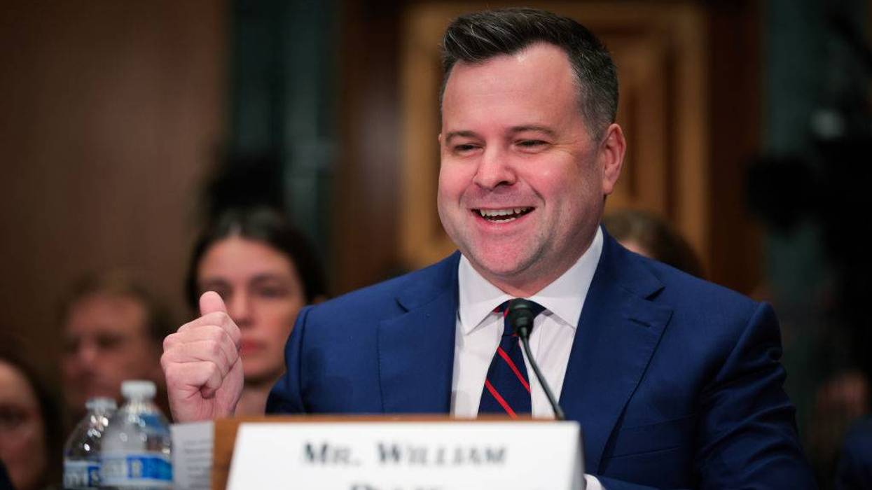 Mr. William Pulte (nameplate) in blue suit, smiling with a raised fist at a formal hearing.