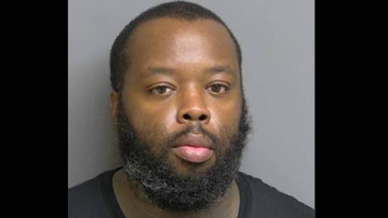 Mugshot: Black man with dark beard, short hair, looking directly at the camera.