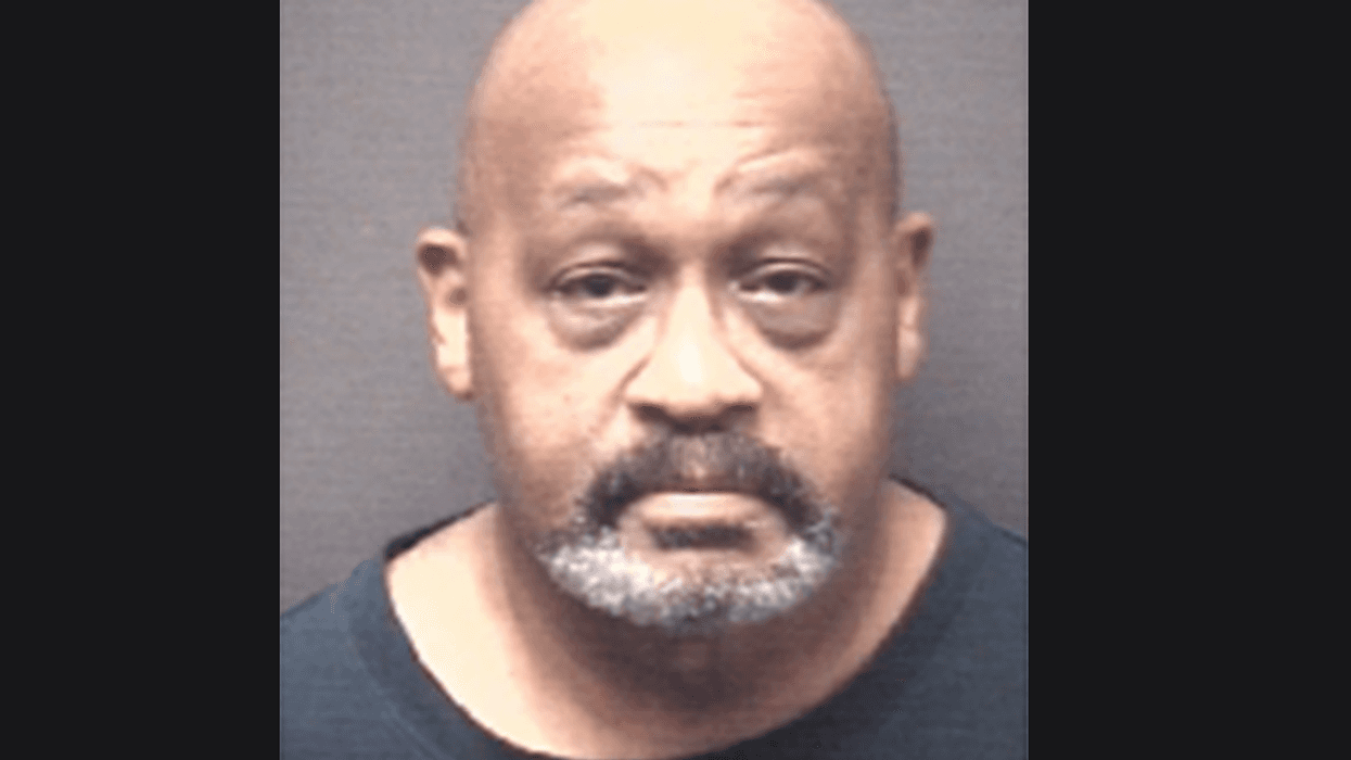 Mugshot of a bald Black man with a graying mustache and goatee, wearing a dark shirt.
