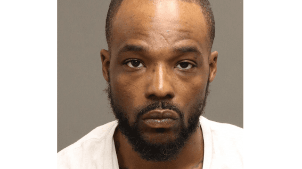 Mugshot of a Black man with a beard and neck tattoos.