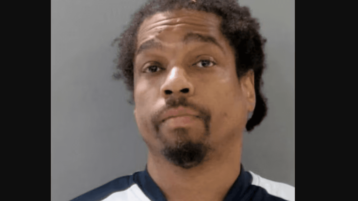 Mugshot of a Black man with curly dark hair and a goatee.