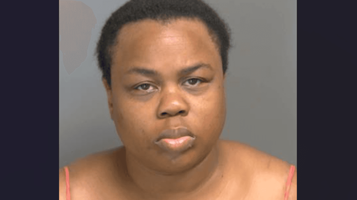 Mugshot of a dark-skinned person with short hair, a slightly pouting expression, wearing thin straps.