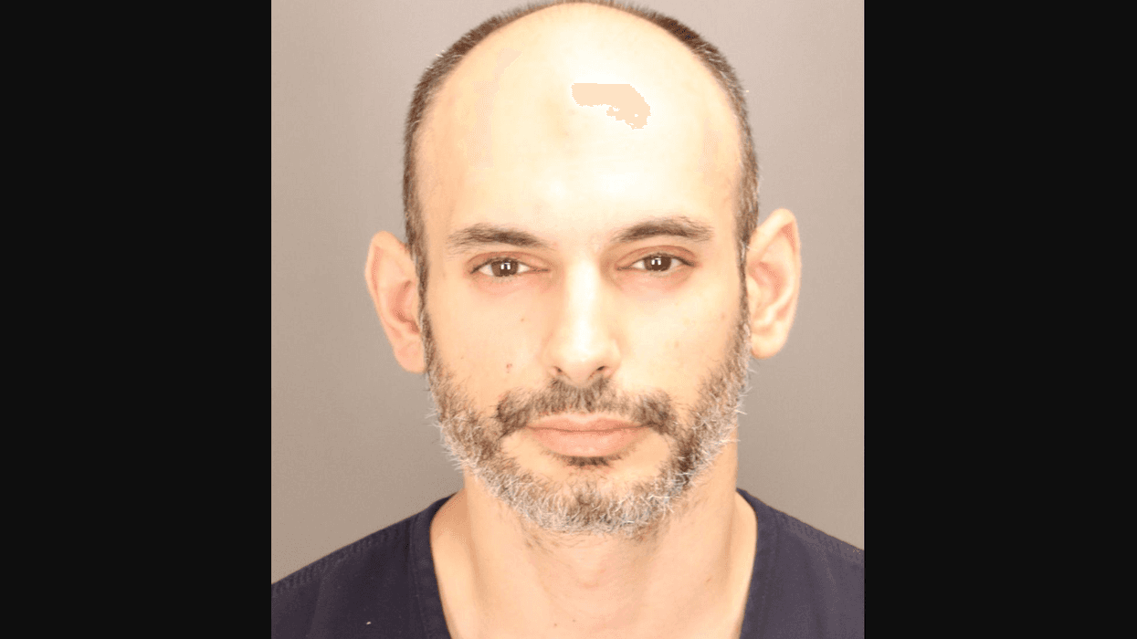 Mugshot of a man with receding hairline, graying beard, and dark eyes.