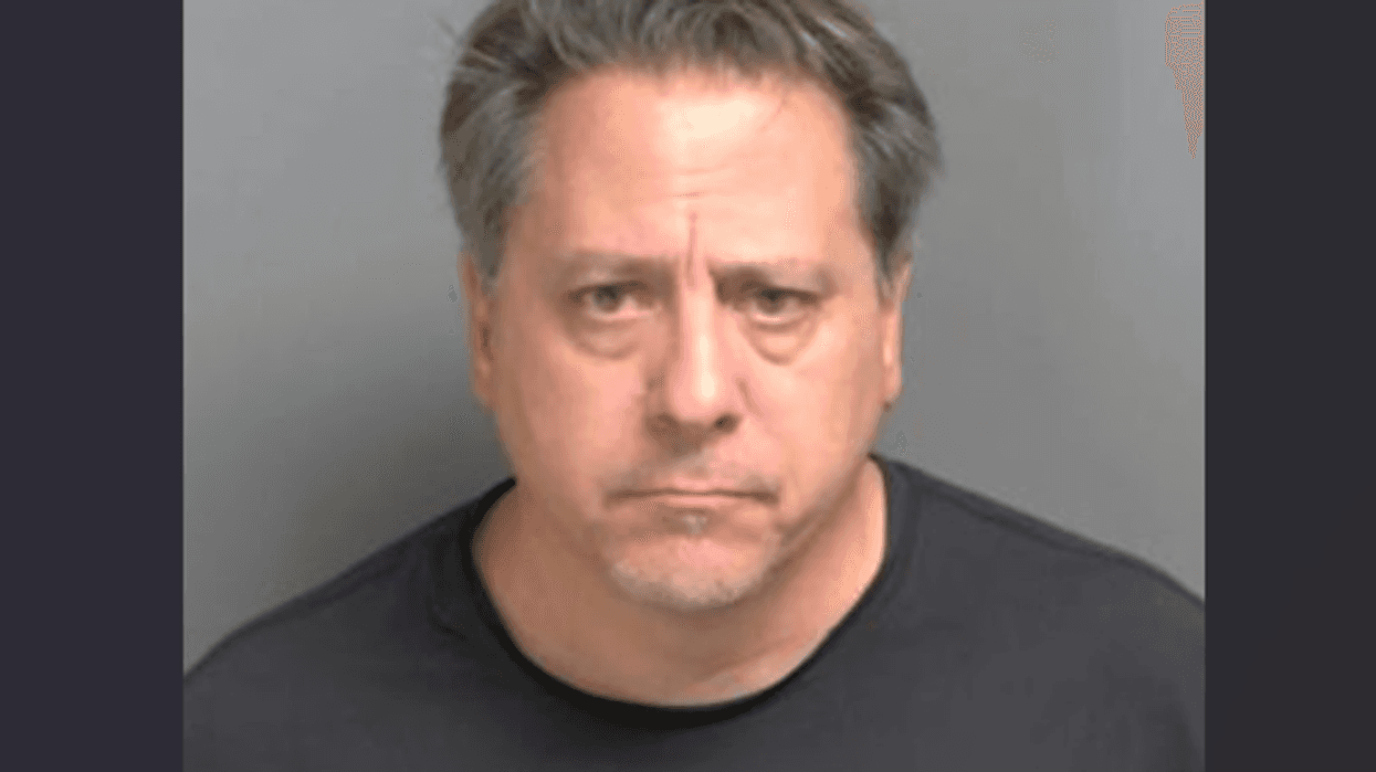 Mugshot of a somber middle-aged man with graying hair, looking directly at the camera.