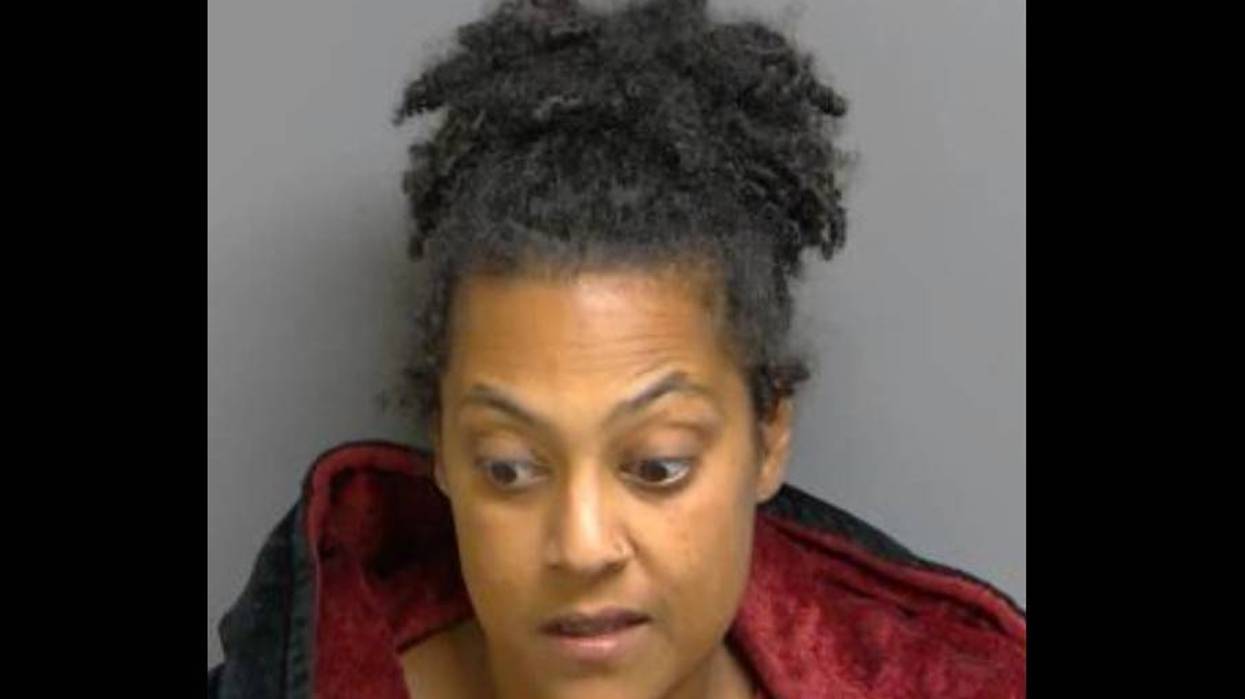 Mugshot of a woman with dark curly hair, looking sideways with a surprised expression.