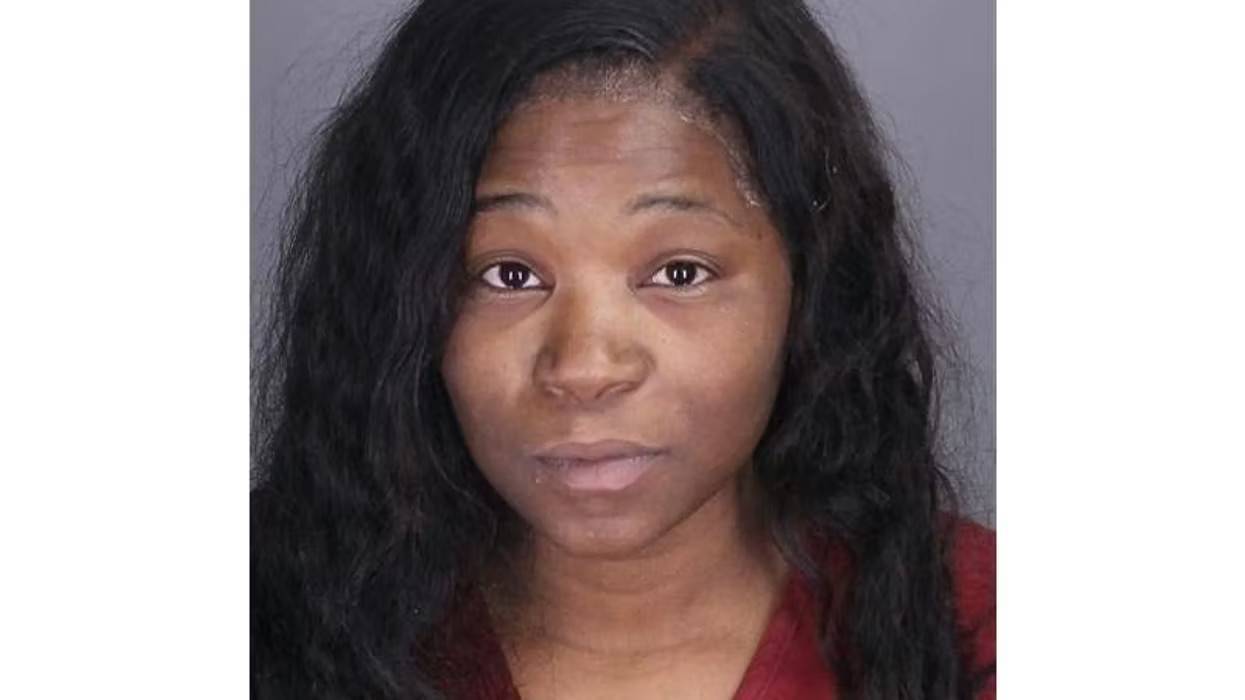 Mugshot of a woman with dark skin and long dark hair, looking directly at the viewer.