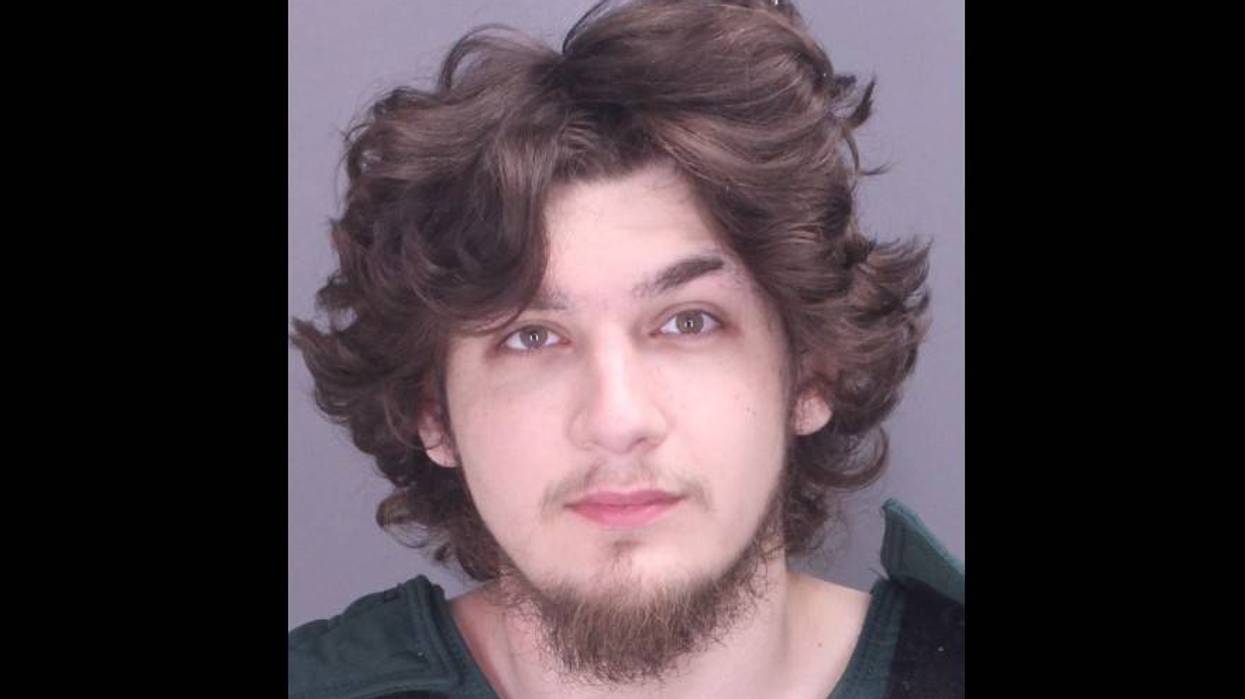 Mugshot: Young man with curly brown hair, light eyes, and a goatee, wearing a green shirt.