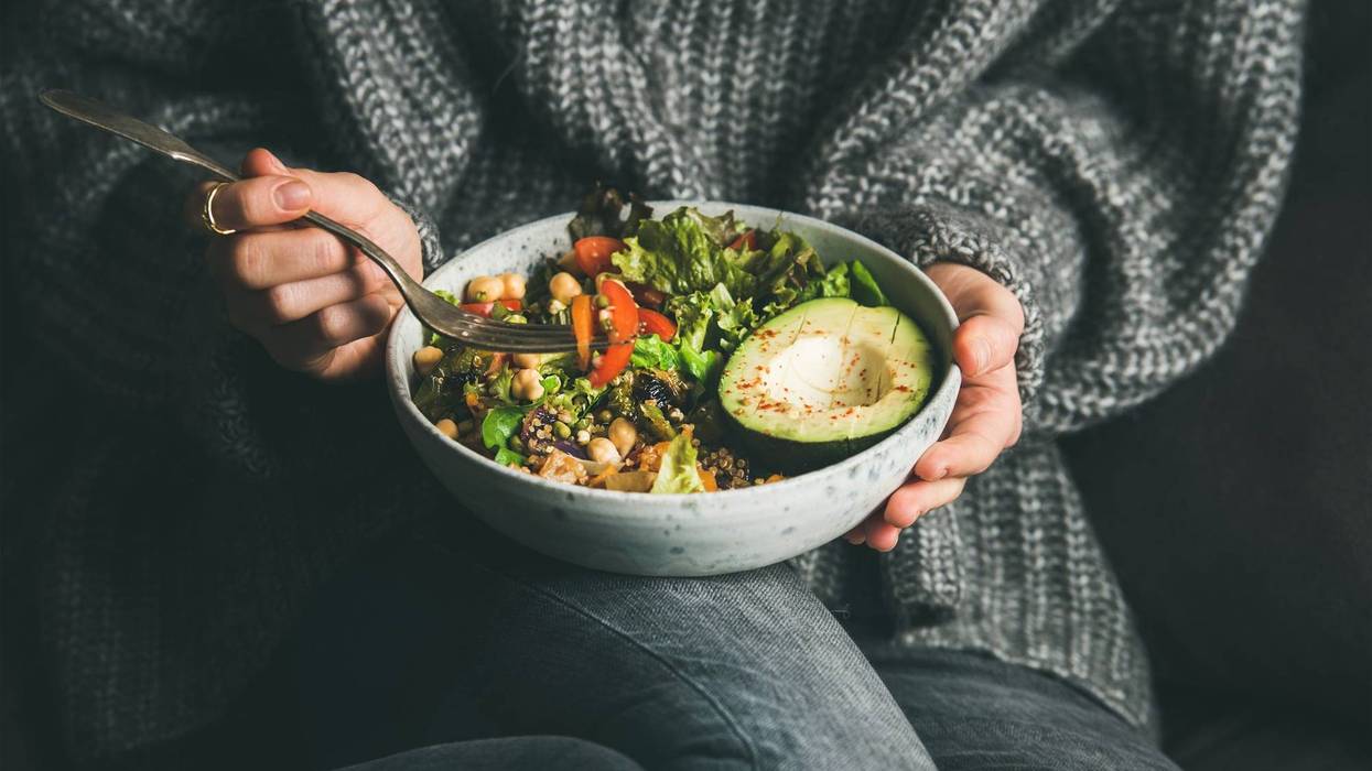 mujer comiendo ensalada con aguacates, granos, vegetales