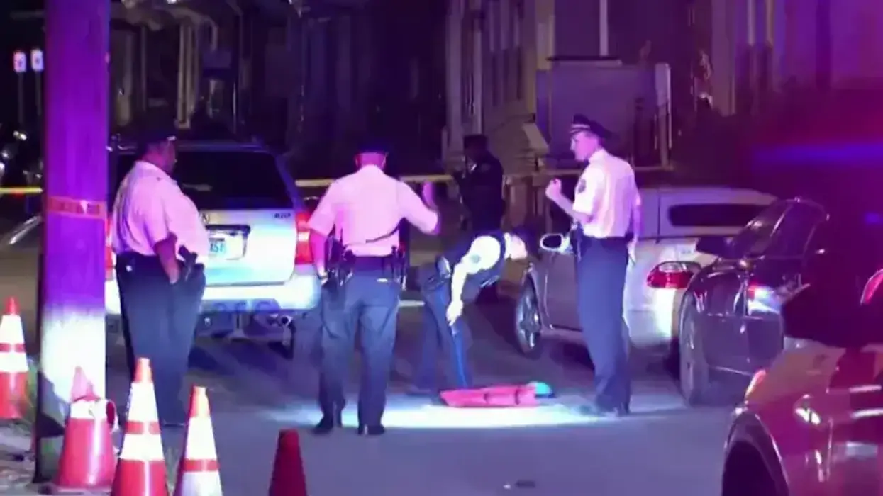 Multiple police officers investigating a street at night, one bends to examine items on the ground.
