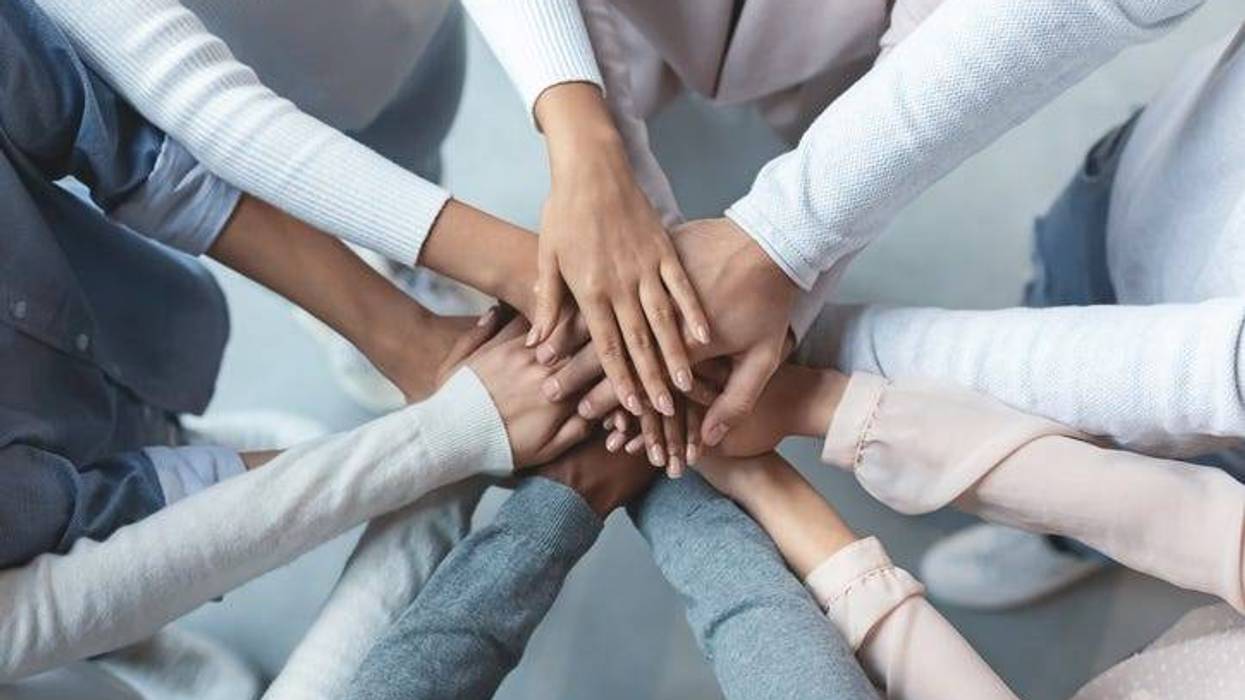Multiracial business team putting hands on top of each other
