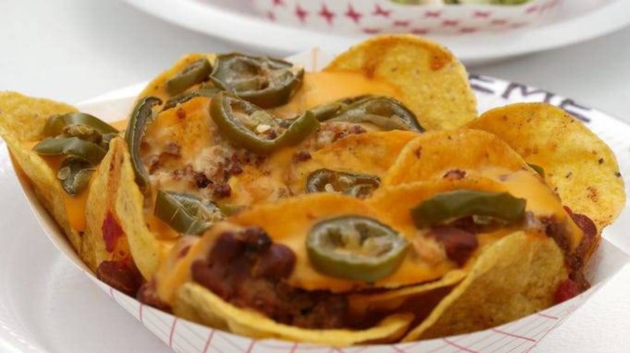 Nachos on a paper plate loaded with jalapeno, meat and melted cheese