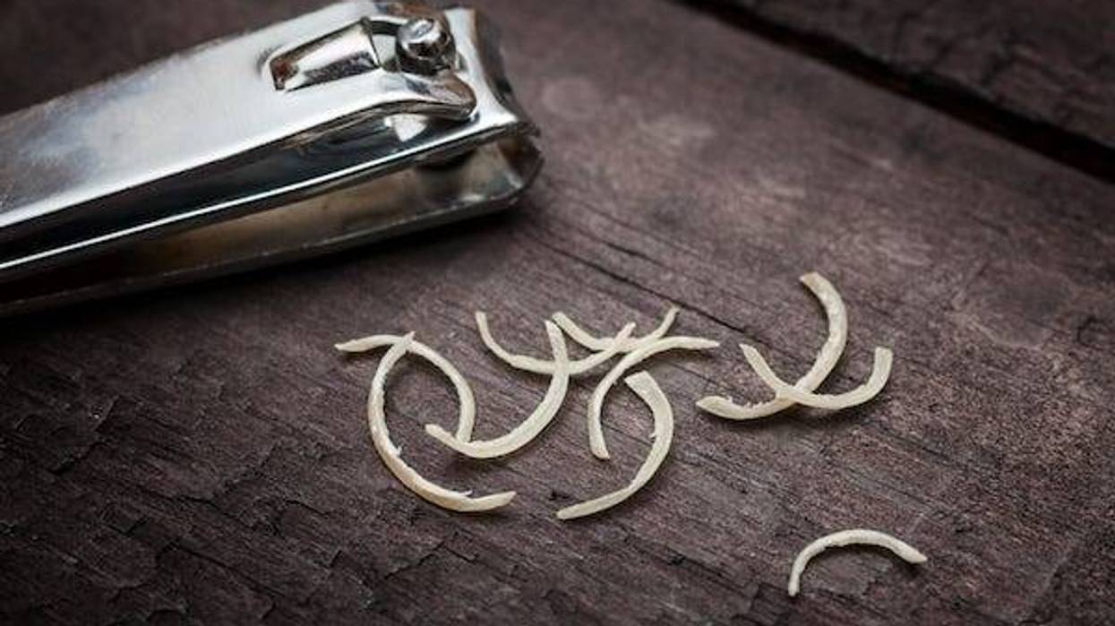 Nail clipper and nail clippings on wooden table