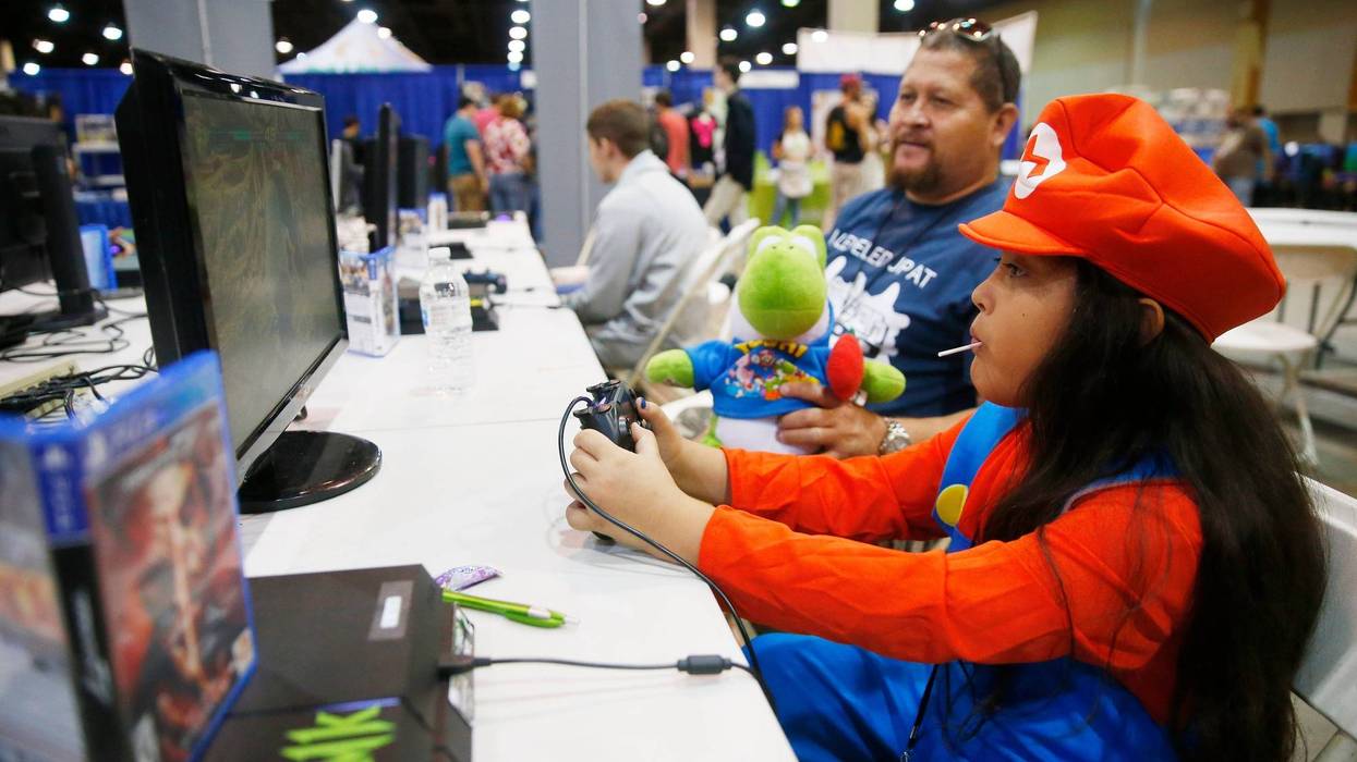 Natalie Menjibar, 9, is watched by her father, Jose, while playing a video game at the 5th Annual Game On Expo at the Phoenix Convention Center on Aug. 11, 2019. Game On Expo