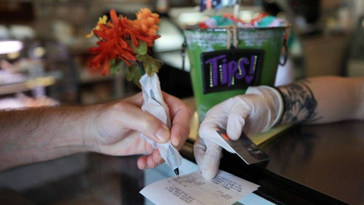 NEW ORLEANS, LA - MARCH 19: A patron uses a pen wrapped in paper to sign a credit card receipt at Angelo Brocato's Italian Ice Cream Parlor due to the coronavirus (COVID-19)