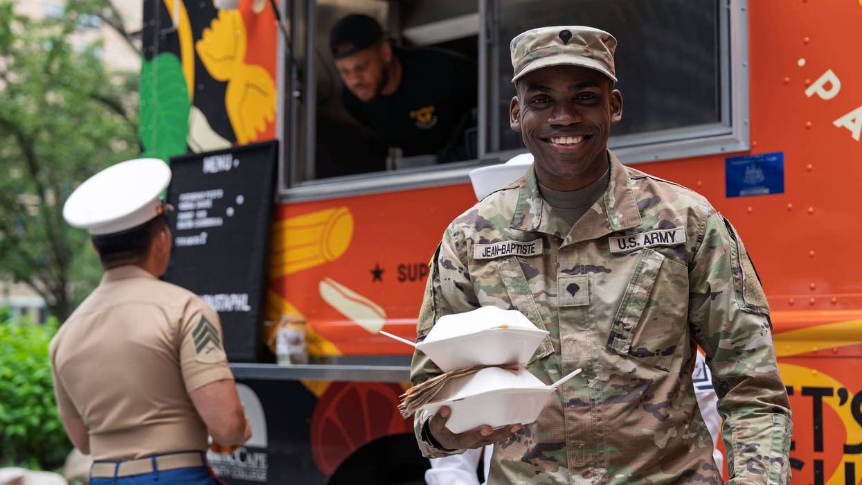 New York Army National Guard recruiter Spc. Standley Jean-Baptiste enjoys street food from the Farina Pasta Bar food truck that was set up at New York City's South Street Seaport as part of the Veterans Food Festival held in the historic district on May 25, 2025