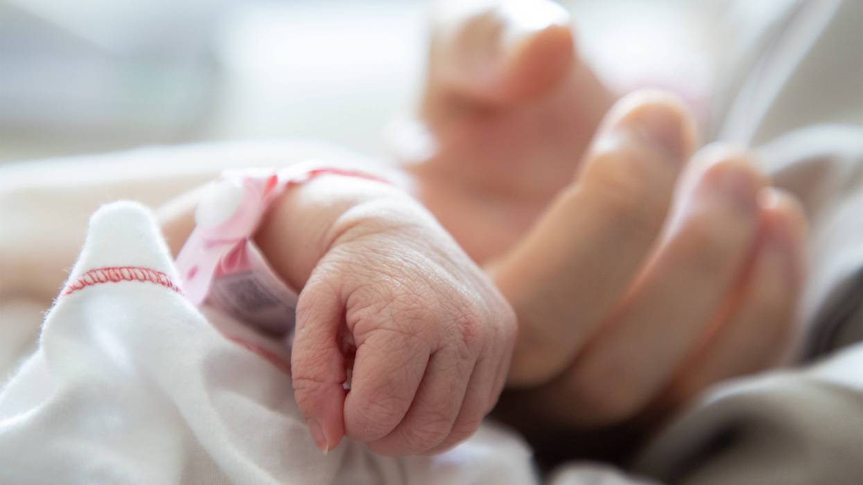 newborn baby hand holding a mother's finger