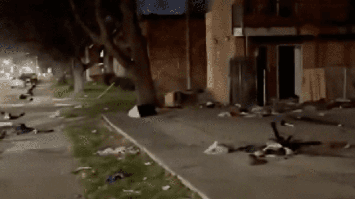 Night scene: a street covered in debris, and damaged buildings.
