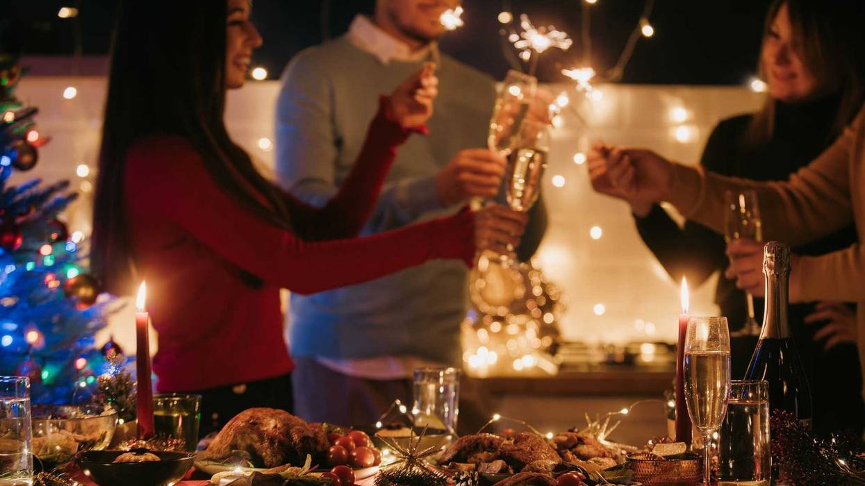 Night shot of people toasting with champagne and holding sparklers while having New Year party at home