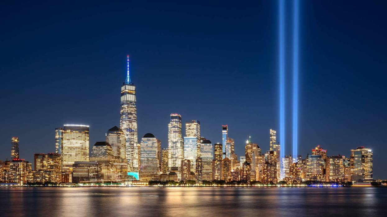 Night view of Lower Manhattan skyline, illuminated skyscrapers and projection into sky of twin beams of light. September 11 Tribute in Light commemoration above the Financial District, New York City