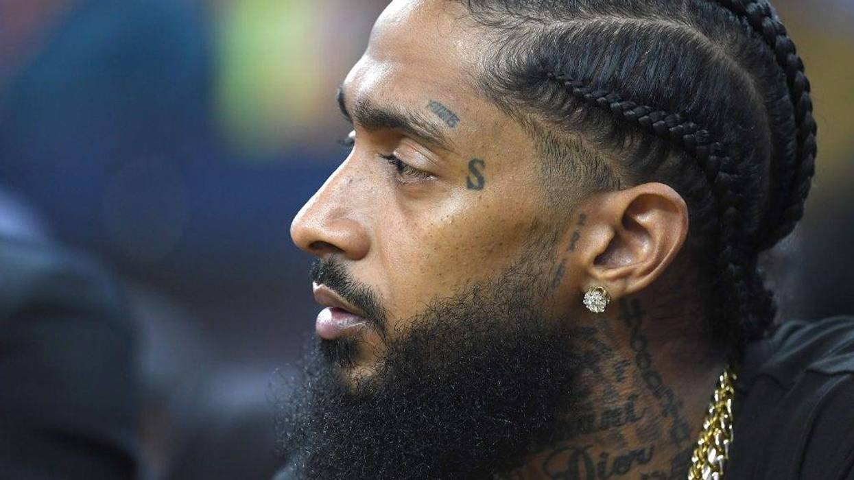 Nipsey Hussle sitting at courtside, looks on during an NBA basketball in Oakland, Calif. in 2018.