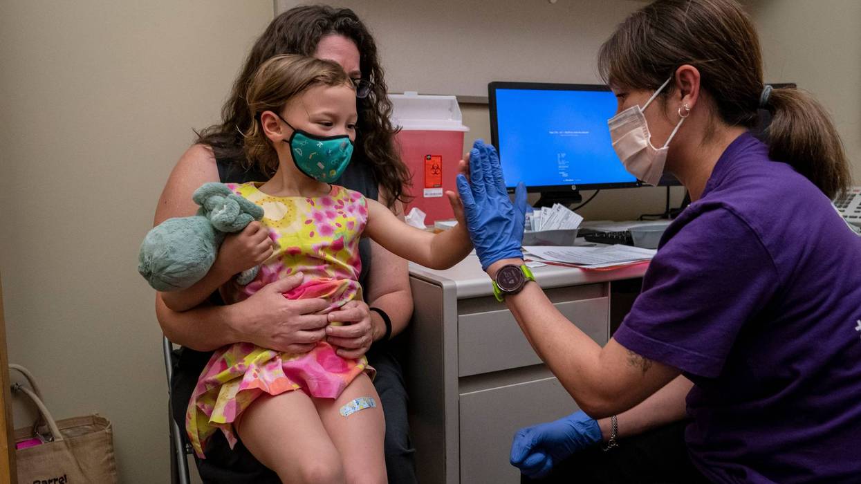 Nora Burlingame, 3, sits on the lap of her mother, Dina Burlingame, and gets a high five from nurse Luann Majeed after receiving her first dose of the Pfizer Covid-19 vaccination at UW Medical Center - Roosevelt on June 21, 2022 in Seattle, Washington.