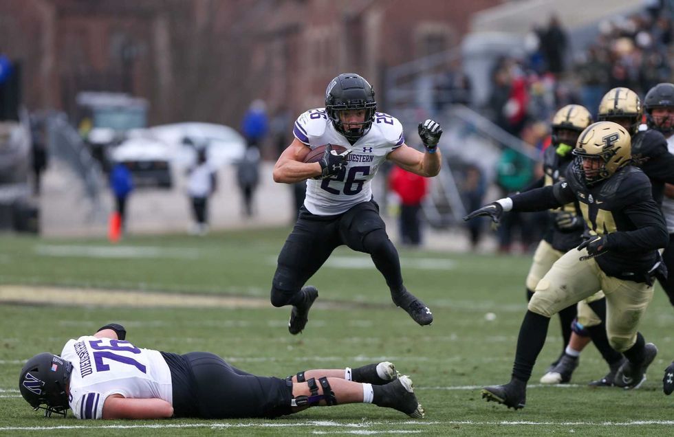 Northwestern Wildcat Evan Hull (26) jumps over offensive lineman Ethan Wiederkehr (76) as he runs away from the Purdue Boilermaker defense during the NCAA football game, Saturday, Nov. 19, 2022, at Ross-Ade Stadium in West Lafayette, Ind. Np1 2868